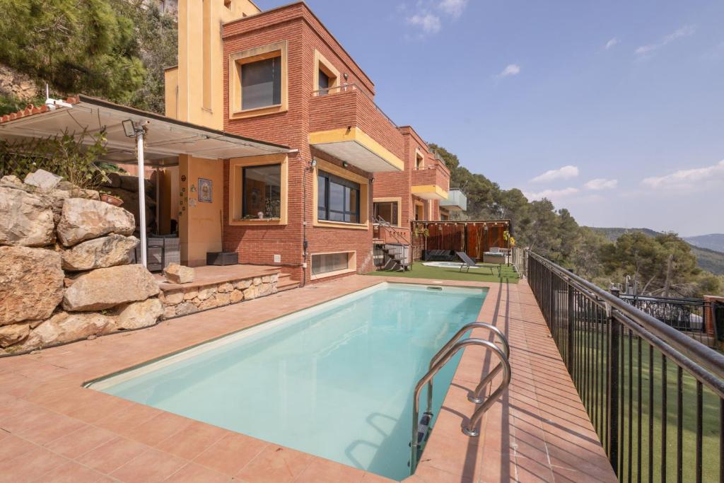 a house with a swimming pool on a balcony at Villa Can Camarassa in Cervelló