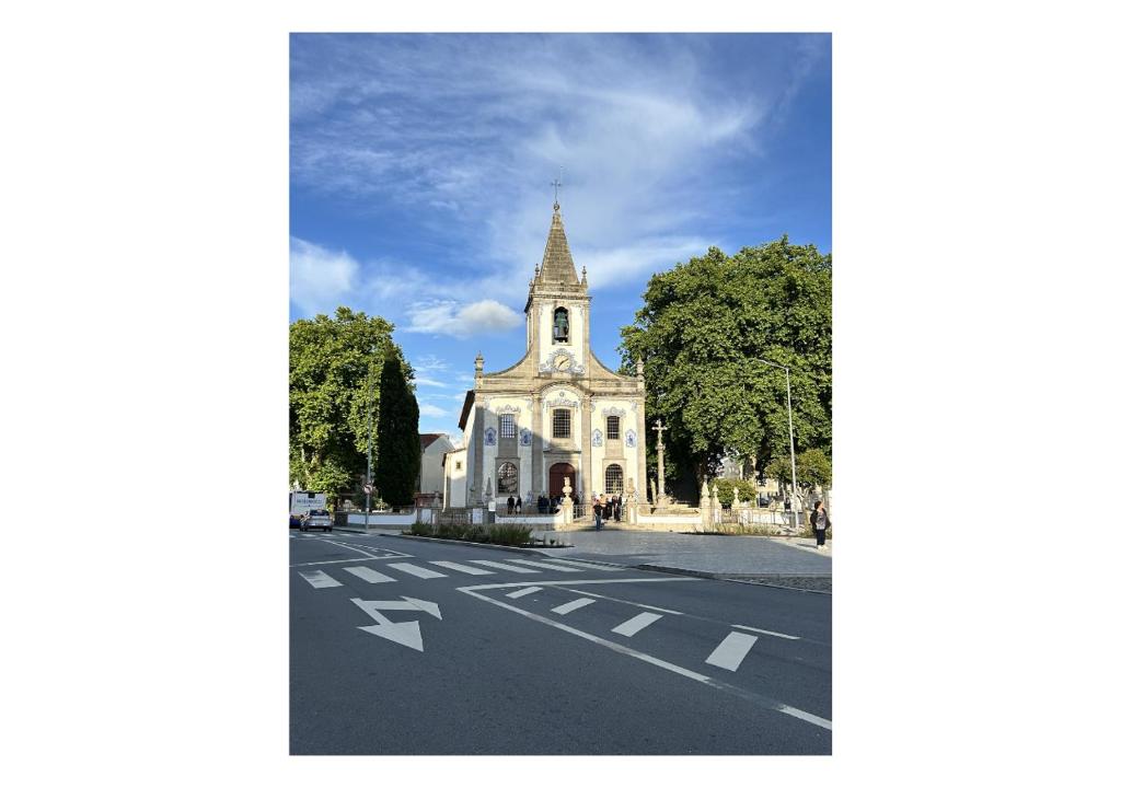 a church with a steeple on the side of a street at Casa Quixote Matosinhos in São Mamede de Infesta