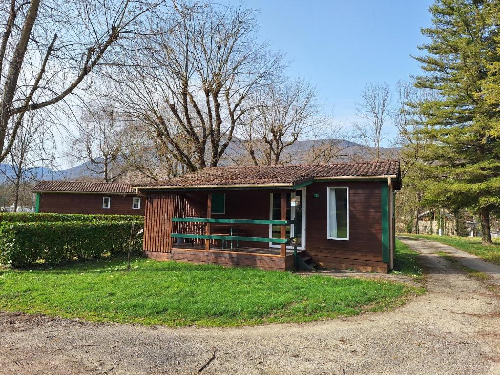 a small house with a porch in a yard at Camping Onlycamp Les Bords de Lyonne in Saint-Jean-en-Royans