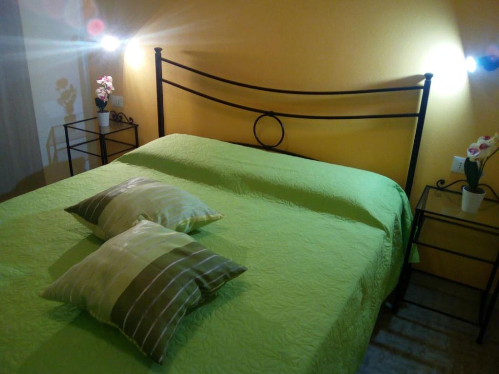 a green bed with two pillows on top of it at Le Domus in Alcamo