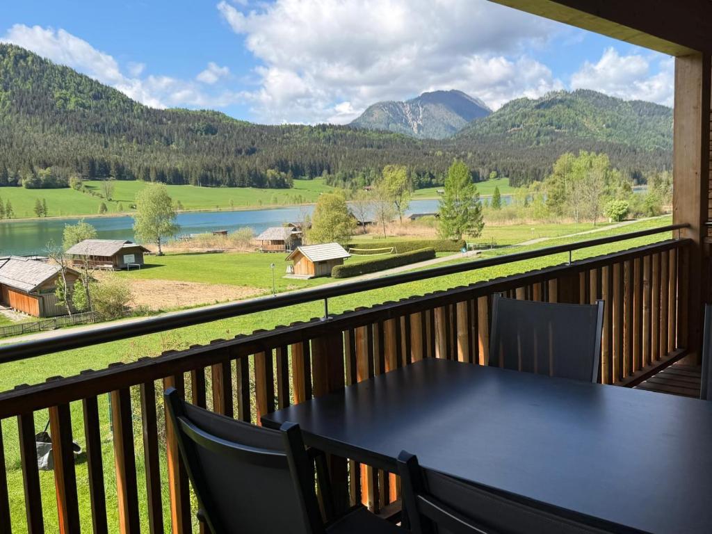 a table on a balcony with a view of the mountains at Premium Apartments am Weißensee in Weissensee