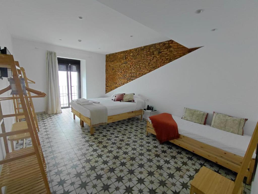a bedroom with two beds and a brick wall at Hotel Rural Casa Cuartel in San Vicente de Alcántara