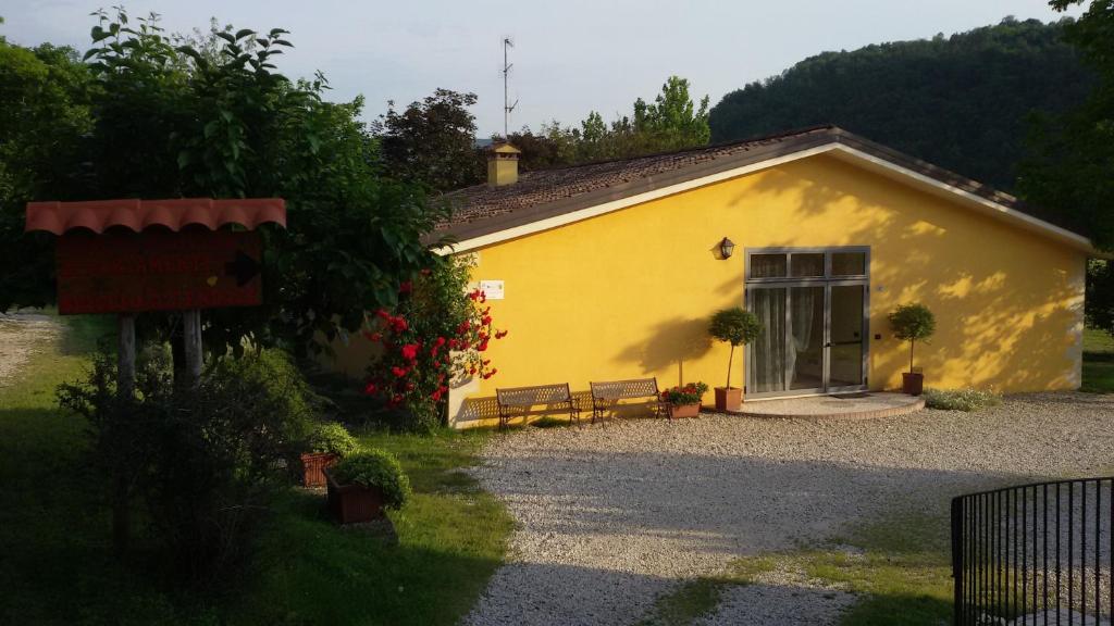 a yellow building with two benches in front of it at Agriturismo Il Lago in Arcugnano