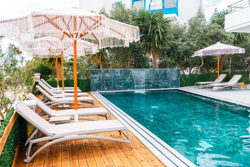 a swimming pool with chairs and umbrellas next to a swimming pool at Vila Malo in Ksamil