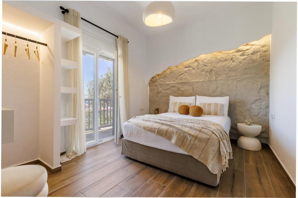 a bedroom with a large bed with a stone wall at Kastri Houses in Panormos Skopelos