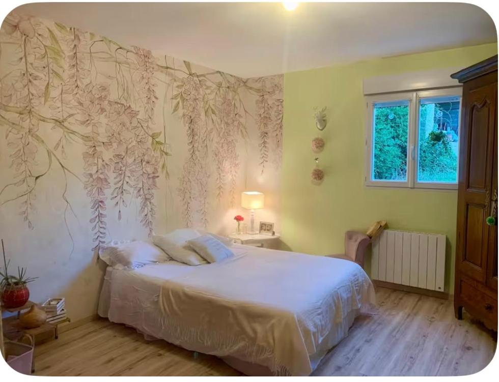 a bedroom with a bed and a wall with flowers at Les Glycines-chambre d'hôtes in Chârost