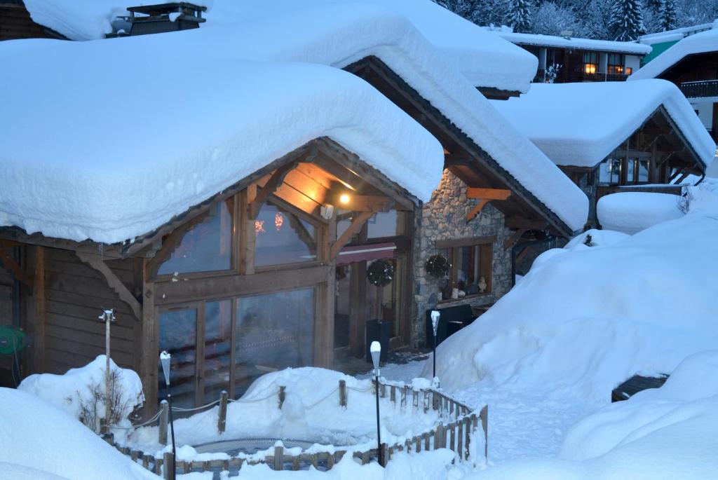 a log cabin in the snow with snow covered roofs at Hôtel et Chalet Au Coin Du Feu Chilly Powder in Morzine