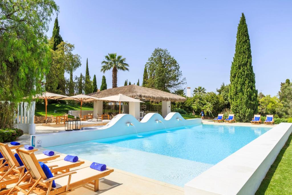 a swimming pool with chairs and a slide at Octant Vila Monte in Moncarapacho