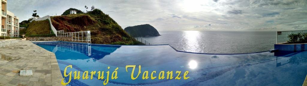 a swimming pool with a view of the ocean at Apartamento Guaruja Vacanze in Guarujá