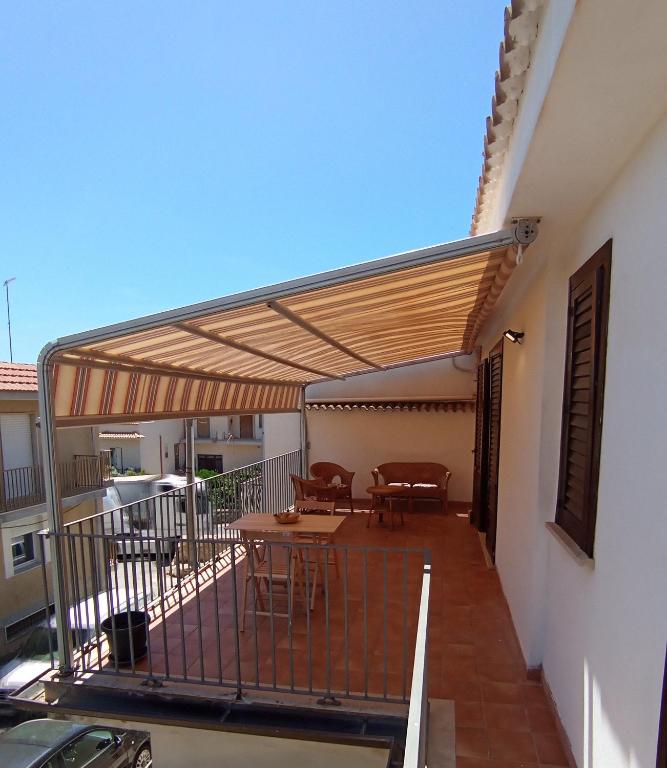 a patio with awning and tables on a balcony at Alba Blu Sampieri in Sampieri