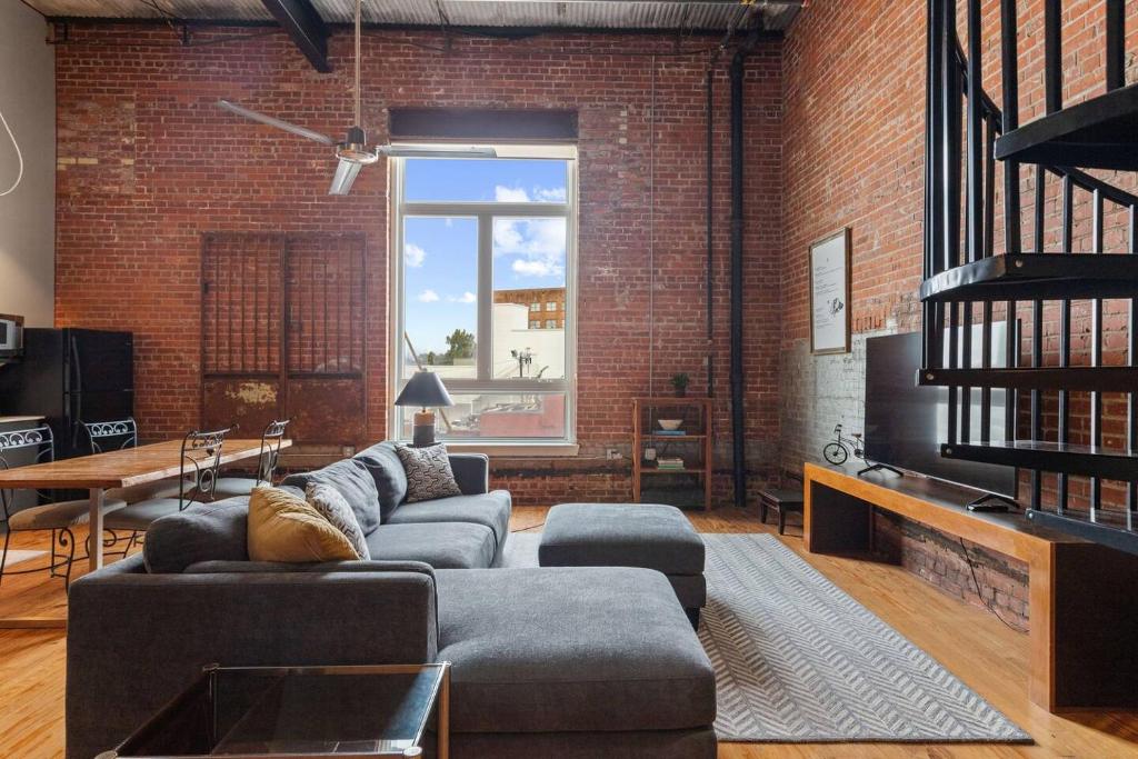 a living room with a couch and a brick wall at Industrial Modern Loft in Downtown Lafayette in Lafayette