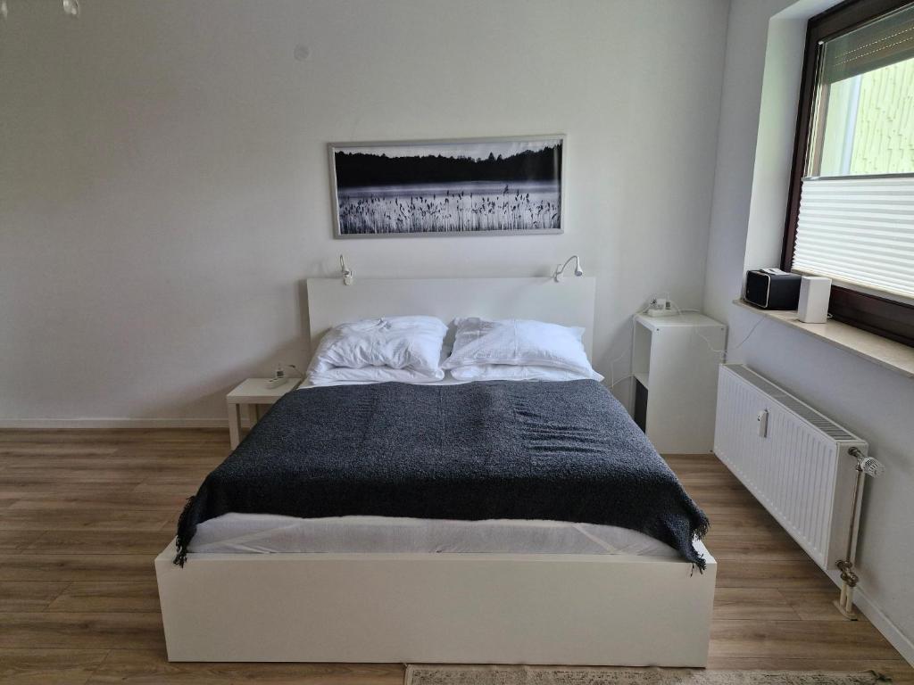 a bedroom with a white bed with a black blanket at Sleep - See - Nah in Klagenfurt