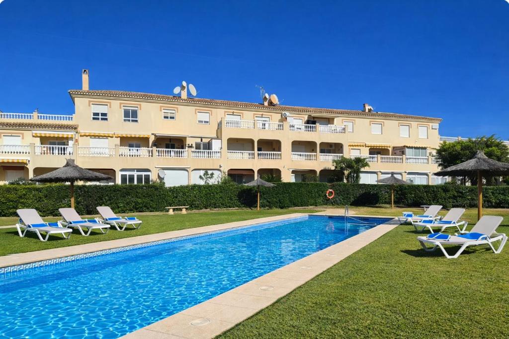 a resort with a swimming pool and chairs and a building at Nuevo Torrox Deluxe Beach & Piscina in Torrox