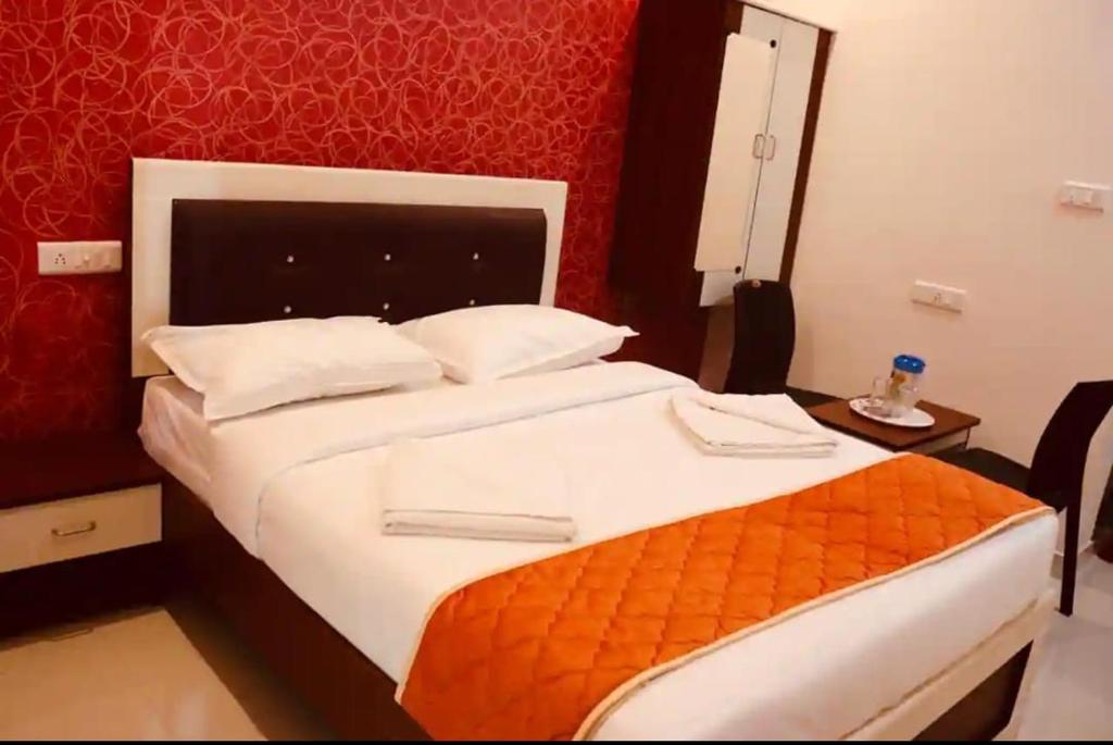 a bedroom with a large bed with an orange blanket at GURU RESIDENCY yercaud in Yercaud