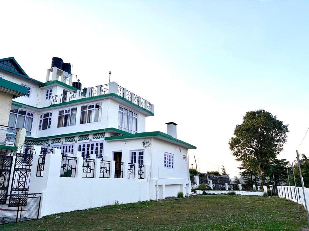 a white house with a fence in front of it at vishwaram Homestay in Chail