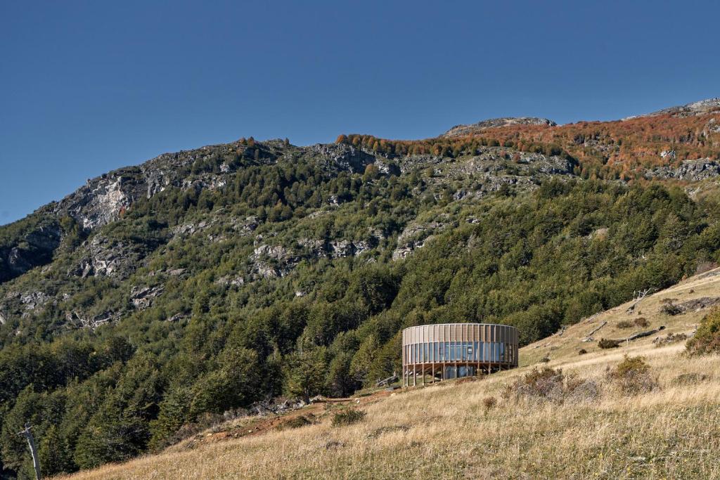 a barn on a hill next to a mountain at Punto Cero Patagonia in Bahía Murta
