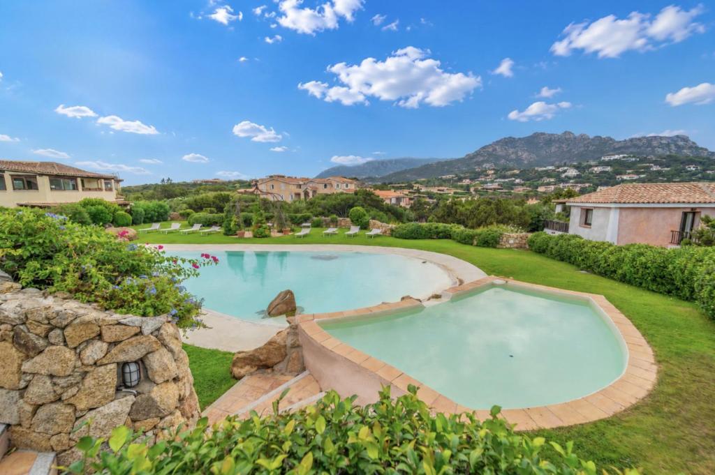 a large swimming pool in a yard with a stone wall at Villa Domo Mea - By Searly in Porto Cervo