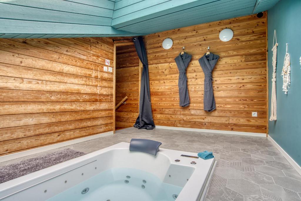 a bath tub in a room with wooden walls at chambre AZZURO avec jacuzzi lit rond et jardin avec piscine in Saint-Martial-sur-Né