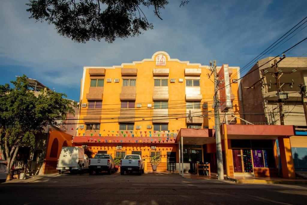 a yellow building with cars parked in front of it at Hotel Santa María in Mazatlán