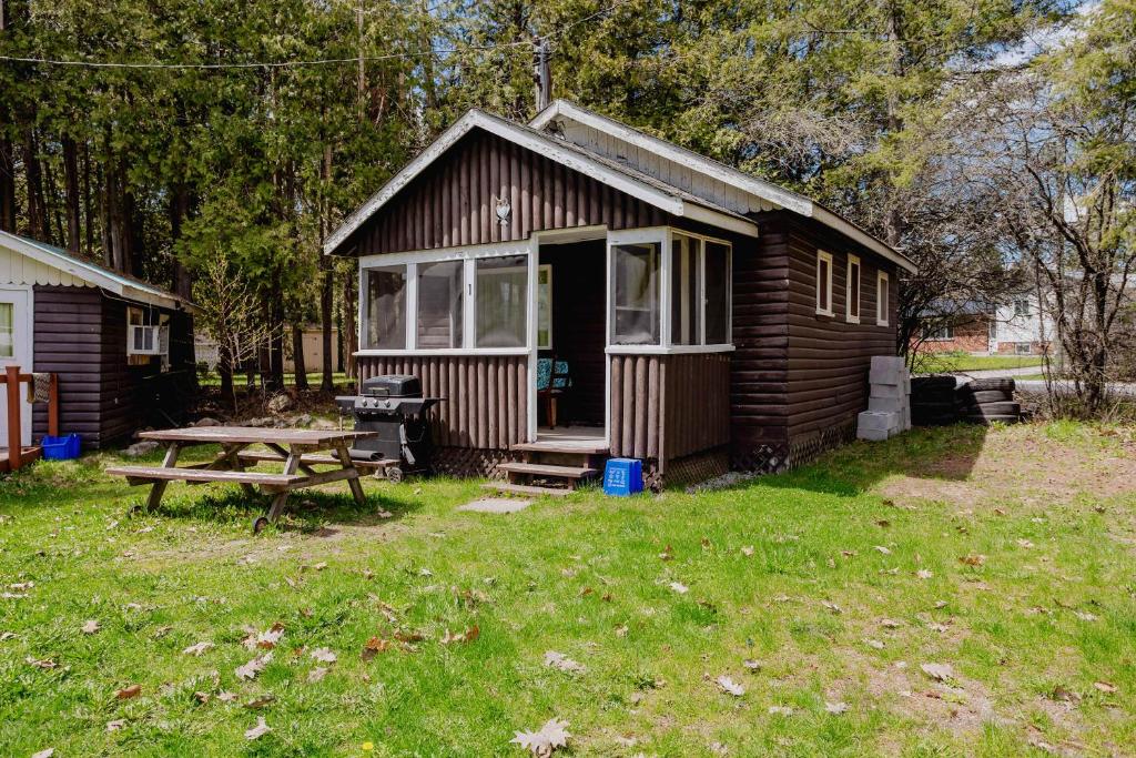 a small cabin with a picnic table in the yard at 2-Bedroom Cottage #1 - Ambleside in Kawartha Lakes