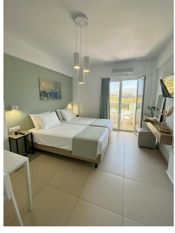 a white bedroom with a bed and a balcony at Kostas Apartments in Stalís