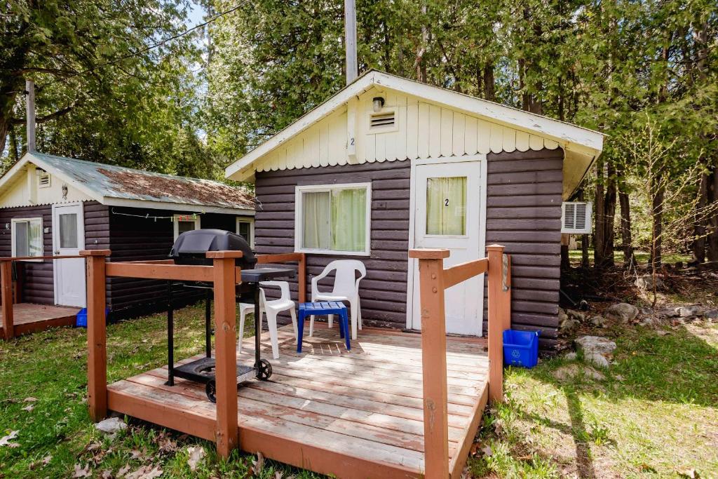a cabin with a grill on a wooden deck at 1-Bedroom Cottage #2 - Ambleside in Kawartha Lakes