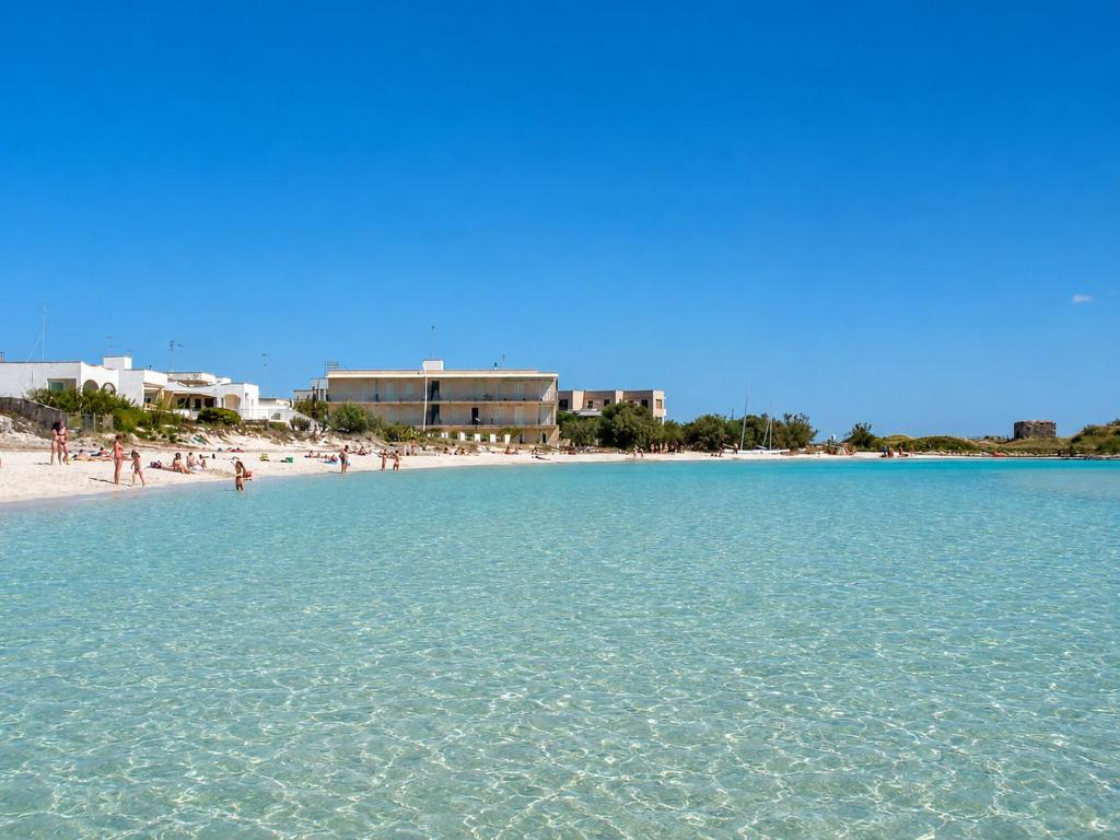 a beach with a group of people in the water at Hotiday Porto Cesareo Laguna in Porto Cesareo