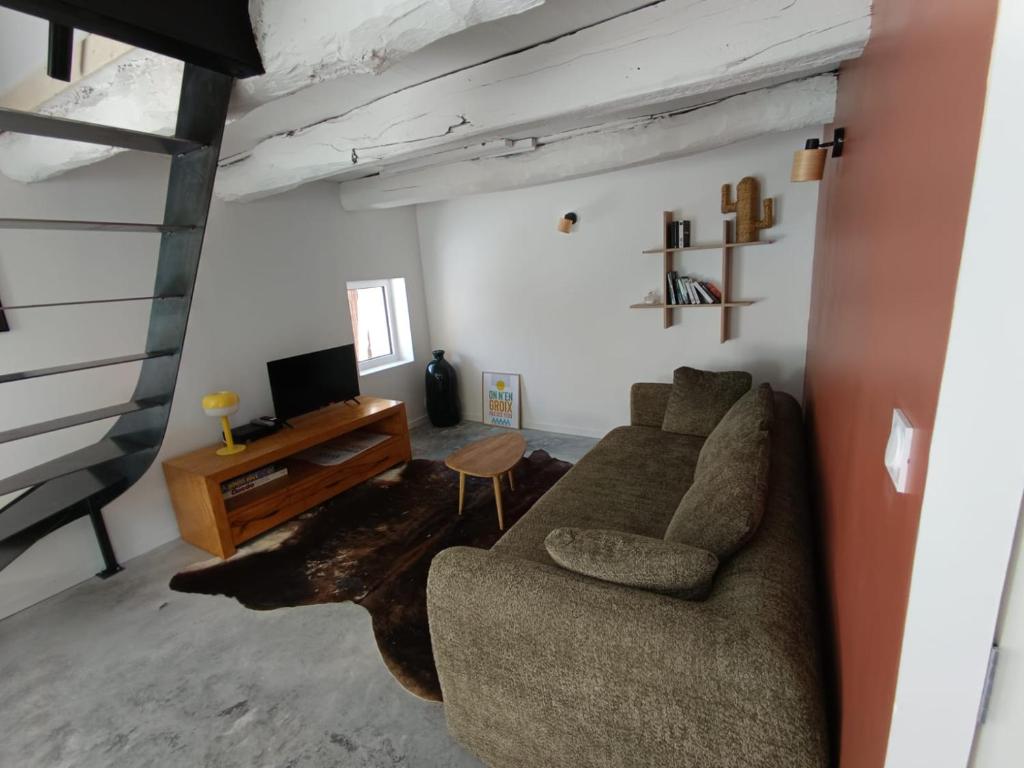 a living room with a couch and a tv at Charmant T2 - 4 couchages à 15mn de la mer in Merlevenez
