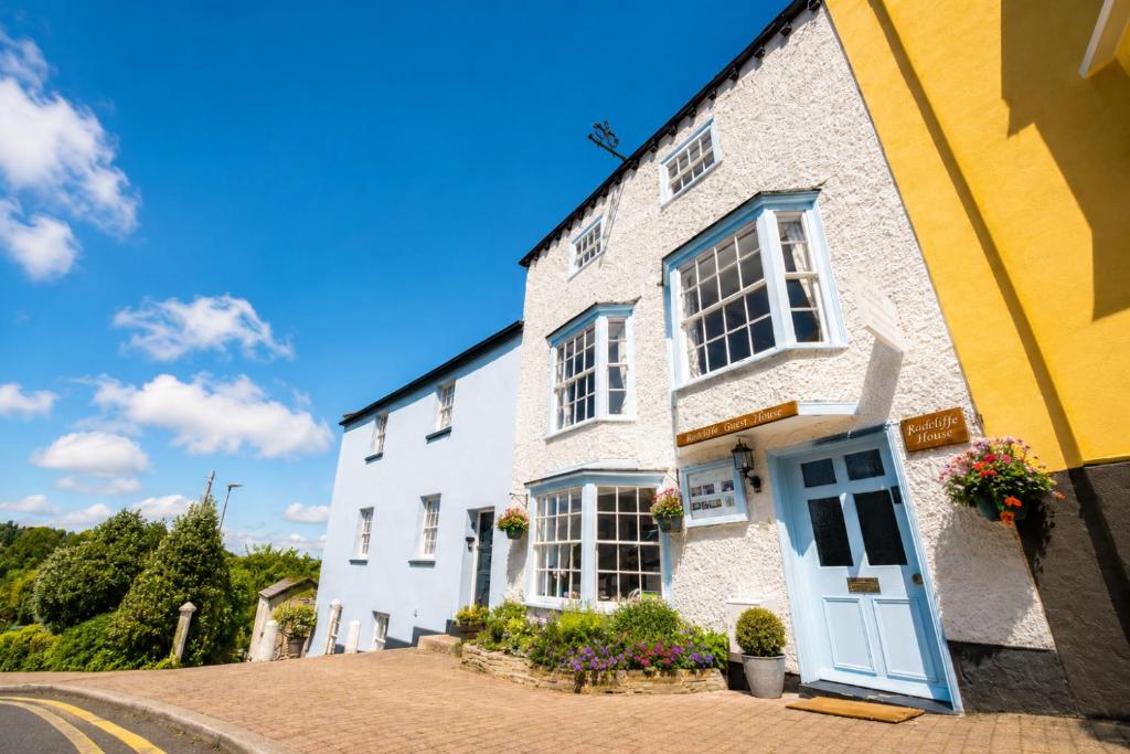 a white house with a blue door on a street at Radcliffe Guest House in Ross on Wye