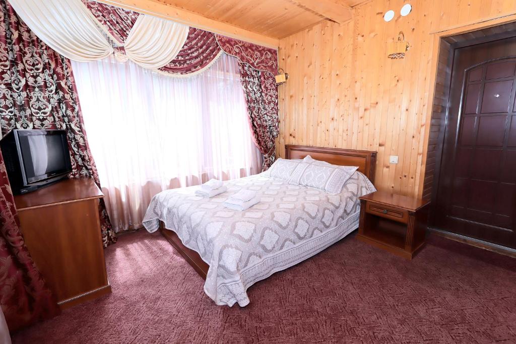 a bedroom with a bed and a tv and a window at Садиба "Едем" in Mykulychyn