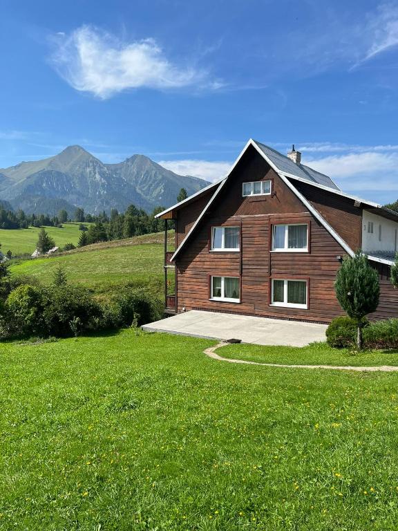 a wooden house in a field with mountains in the background at U Milušky in Ždiar