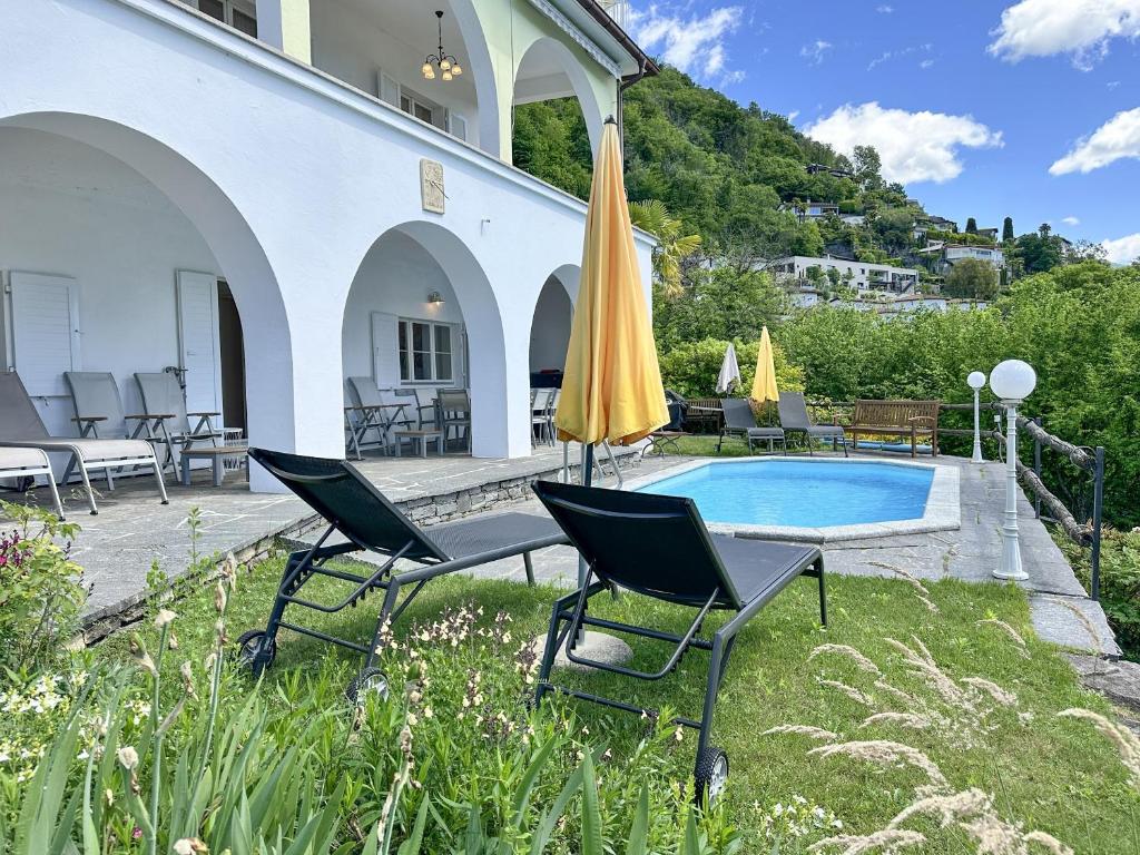 a patio with chairs and an umbrella and a pool at Villa Grande Dame by Fewotessin in Minusio