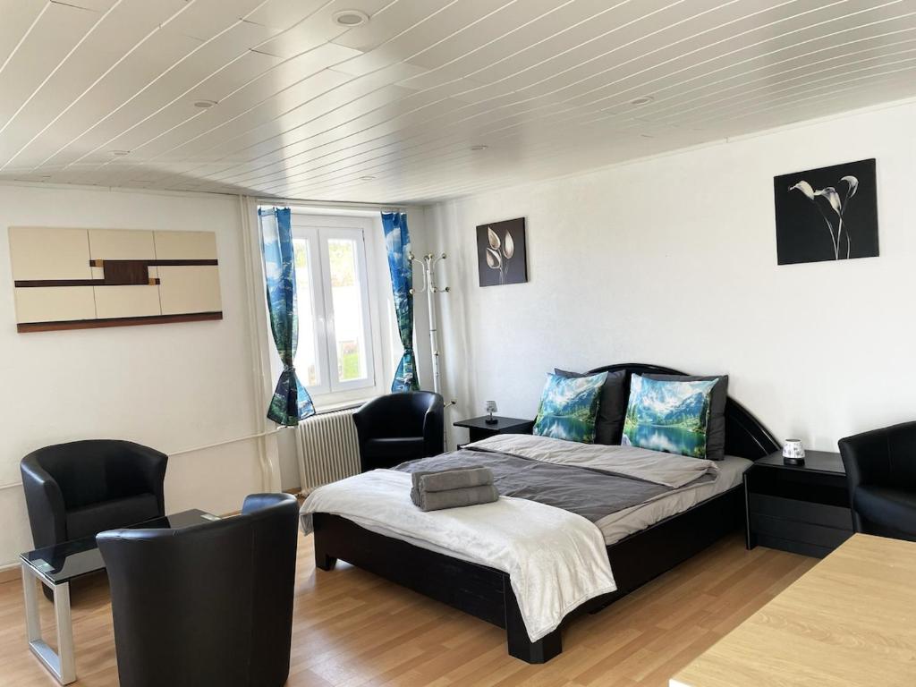 a bedroom with a bed and chairs in it at 1 appartement au centre de Saignelégier in Saignelégier