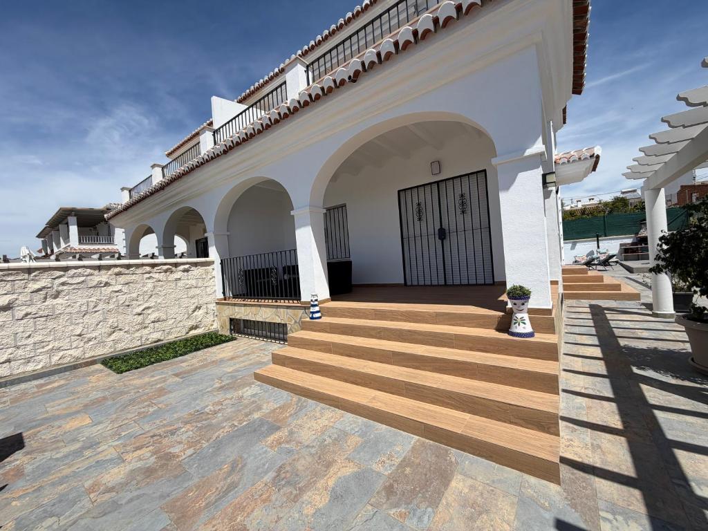 a white house with wooden stairs and a door at Niza Beach Sunset Stay in Málaga
