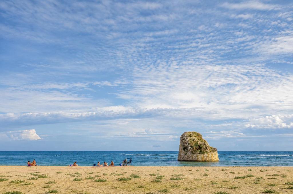 a large rock sitting on a beach near the ocean at Hotiday Torre Pali Spiaggia in Torre Pali