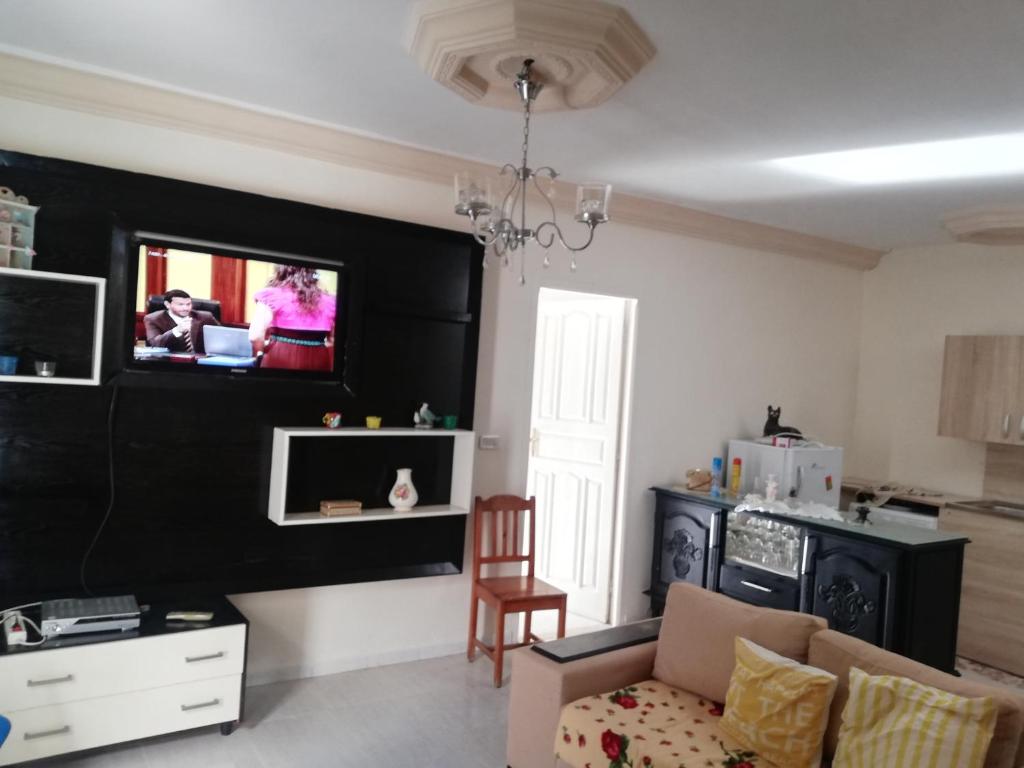 a living room with a couch and a tv on a wall at Binch in El Haouaria