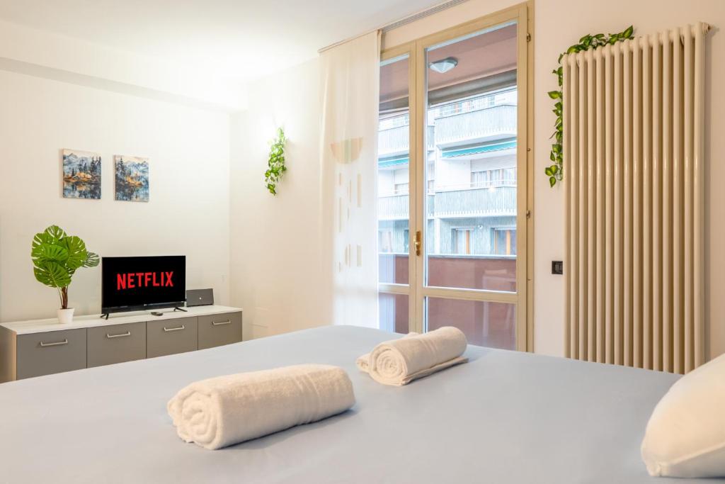 a white bedroom with two towels on a bed at Lake Como - Front Station - Lake at 2 min - Wifi in Lecco