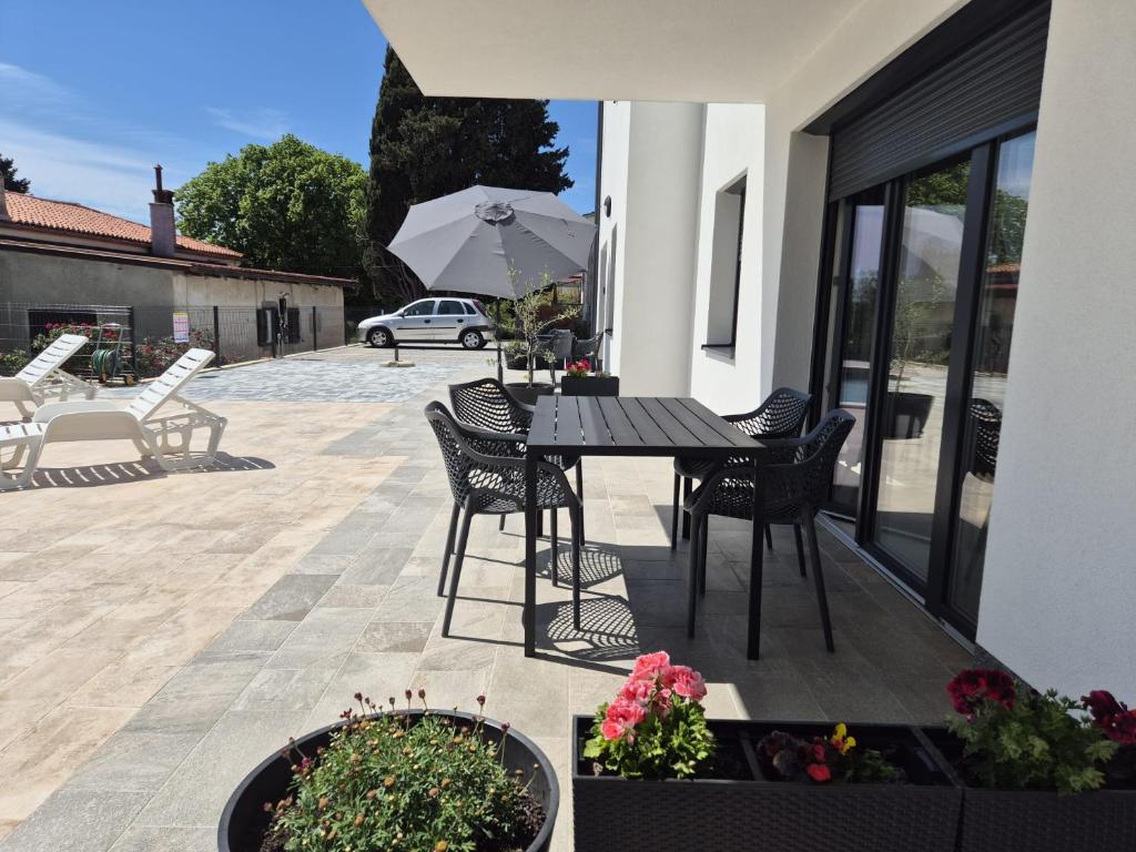 a patio with a table and chairs and an umbrella at Apartment Natalija A2 ground floor in Krk