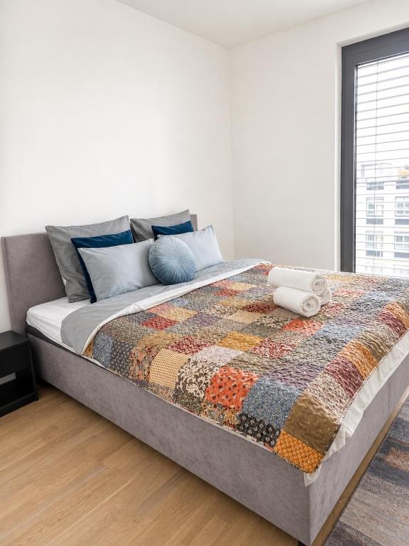 a bed with a quilt on it in a bedroom at SunsetSkylineApartment in Nivy