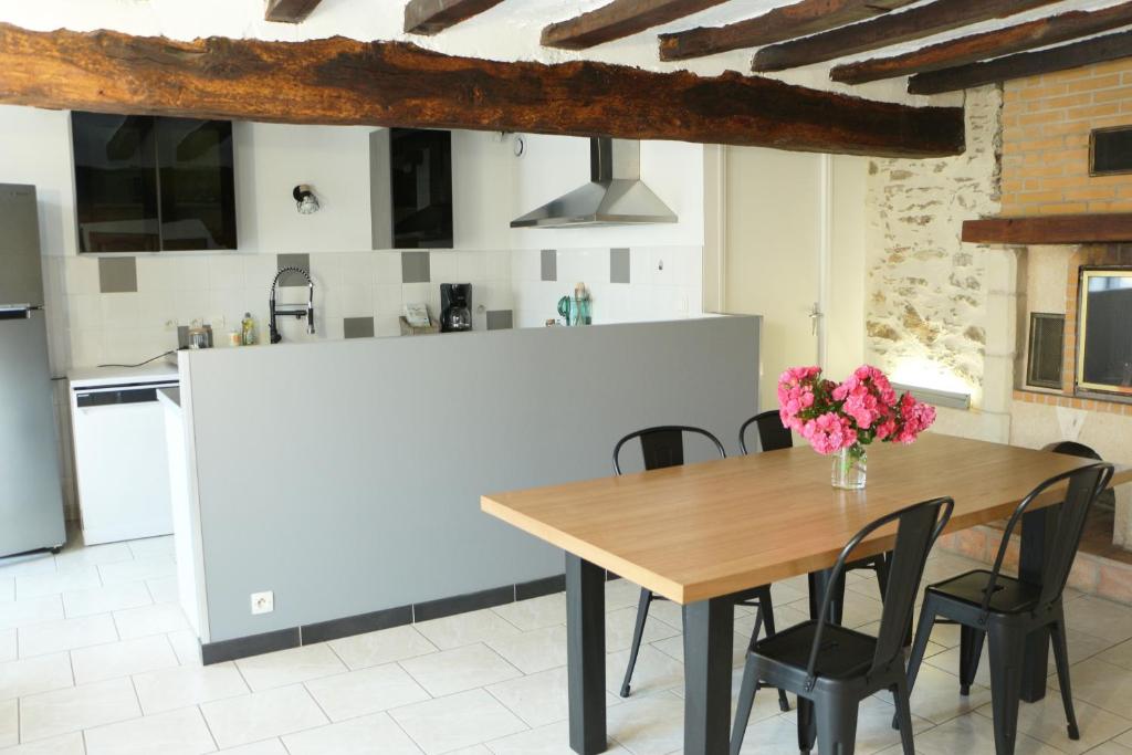 a kitchen and dining room with a wooden table and chairs at Gîte de l'Aubinière in Brissac-Quincé