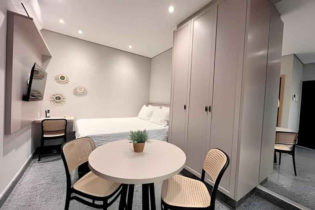 a small room with a table and chairs and a bed at Santorini Urban Studio • conforto e estilo in Londrina