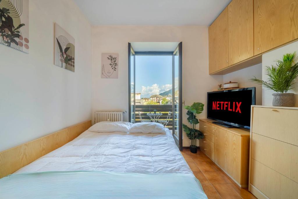 a bedroom with a bed and a tv and a window at Vista piste da sci - Aprica Centro - Piste a 2 min, Wifi in Aprica