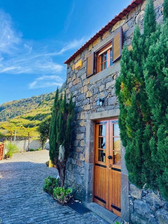 a stone house with a wooden door and trees at Ribeira da Janela Paradise View in Porto Moniz