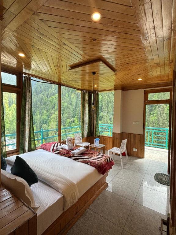 a bedroom with a large bed in a room with windows at Venky's Shoja in Jibhi