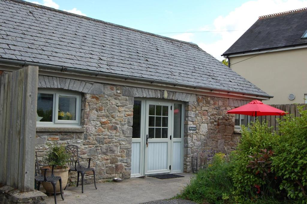 a stone building with a white door and a patio at Dryslwyn Cottage in Carmarthen