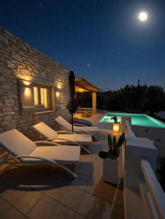 a group of lounge chairs next to a pool at night at Villa Giorgianna -near Aliki beach with pool in Aliki