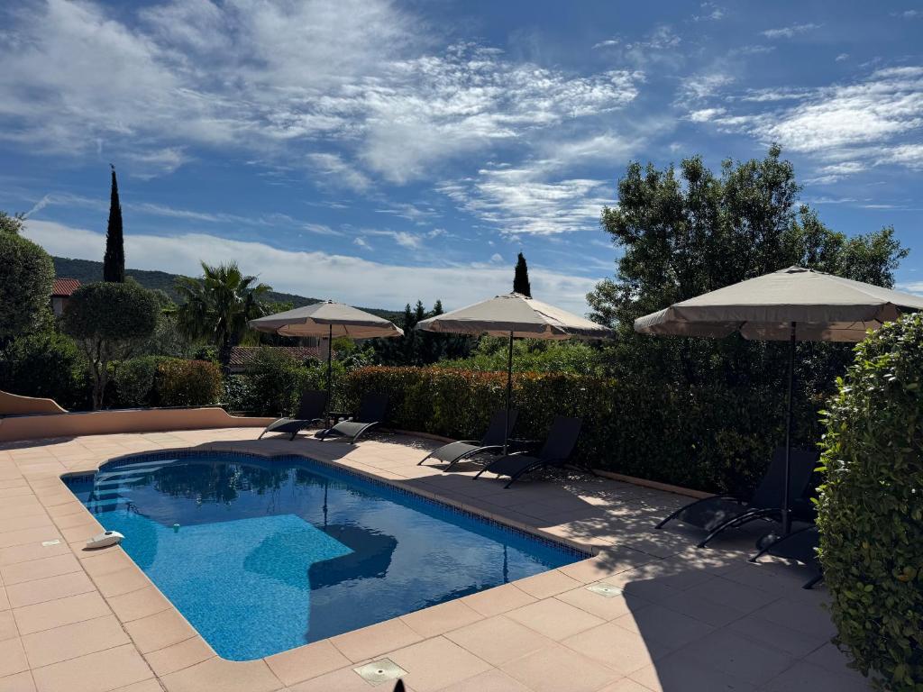 a swimming pool with chairs and umbrellas at Villa sainte maxime golfe de Saint Tropez in Sainte-Maxime