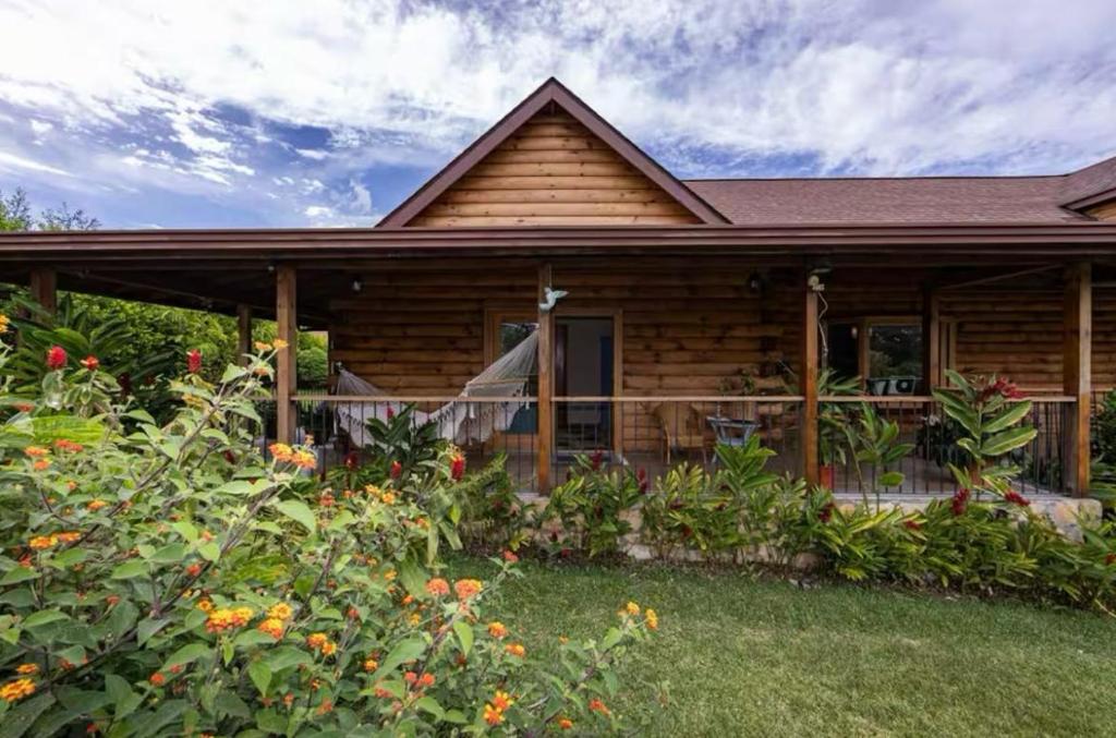 a wooden house with a porch and some flowers at Blue Mountains Cabin in Boquete