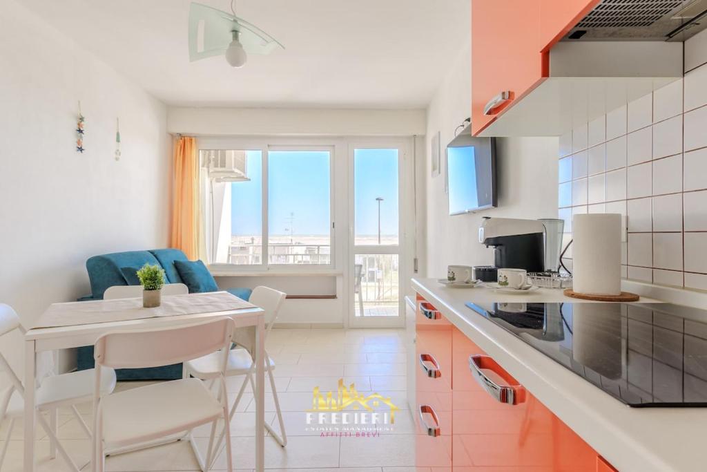 a kitchen with a table and chairs in a kitchen at Lido degli Estensi Fronte Mare e Balcone in Comacchio