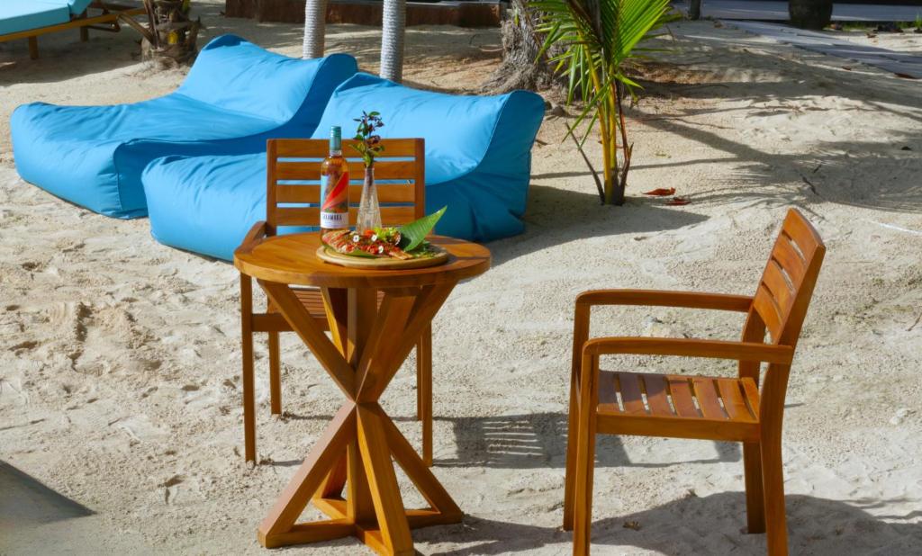 ein Tisch, zwei Stühle und eine Couch am Strand in der Unterkunft Castello Beach Hotel in Grand'Anse Praslin